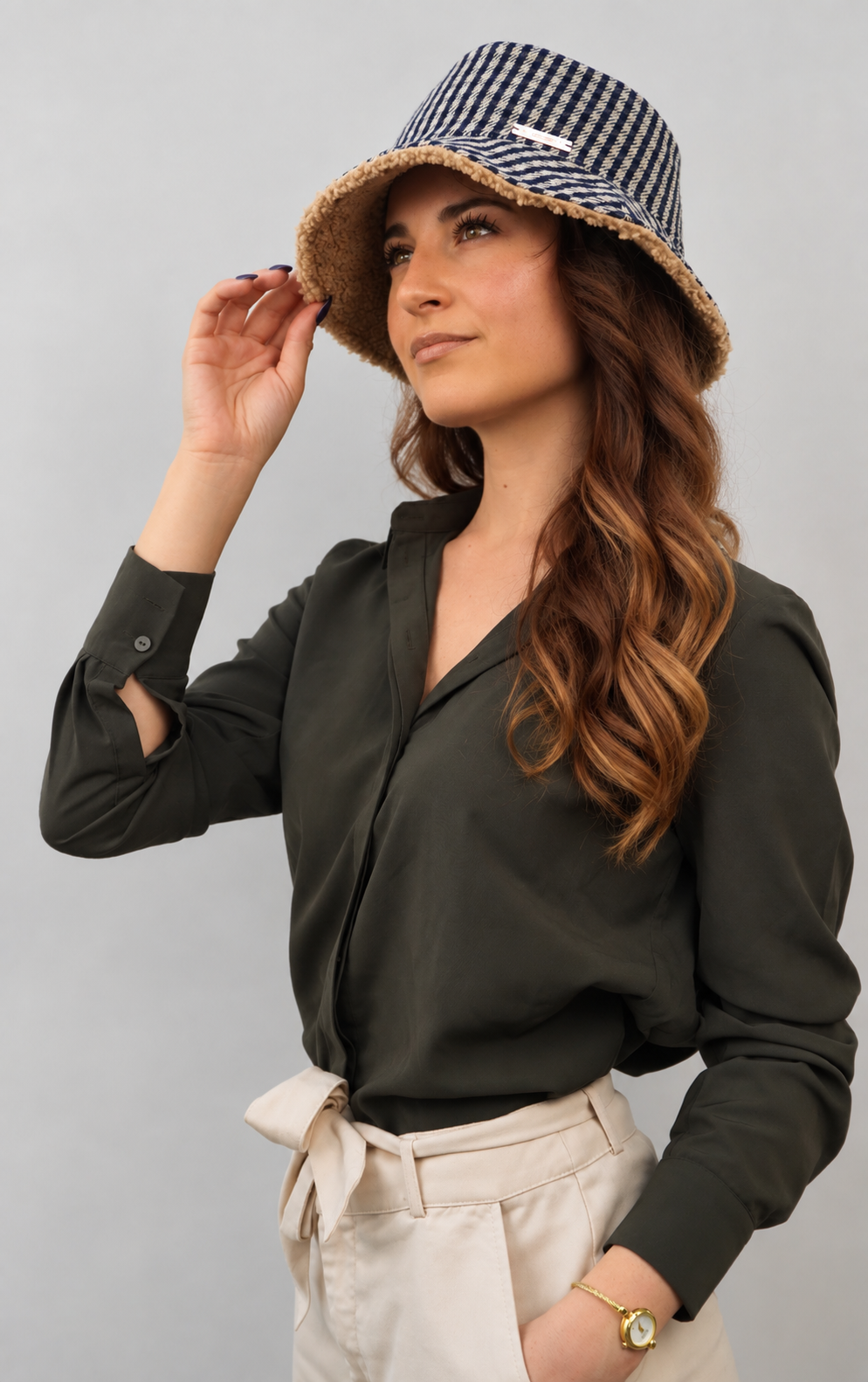 Cappello bucket hat Mabel del brand Accapofitto, realizzato con tessuto a quadretti blu e beige all'esterno e con tessuto teddy color cammello all'interno. Indossato da una modella