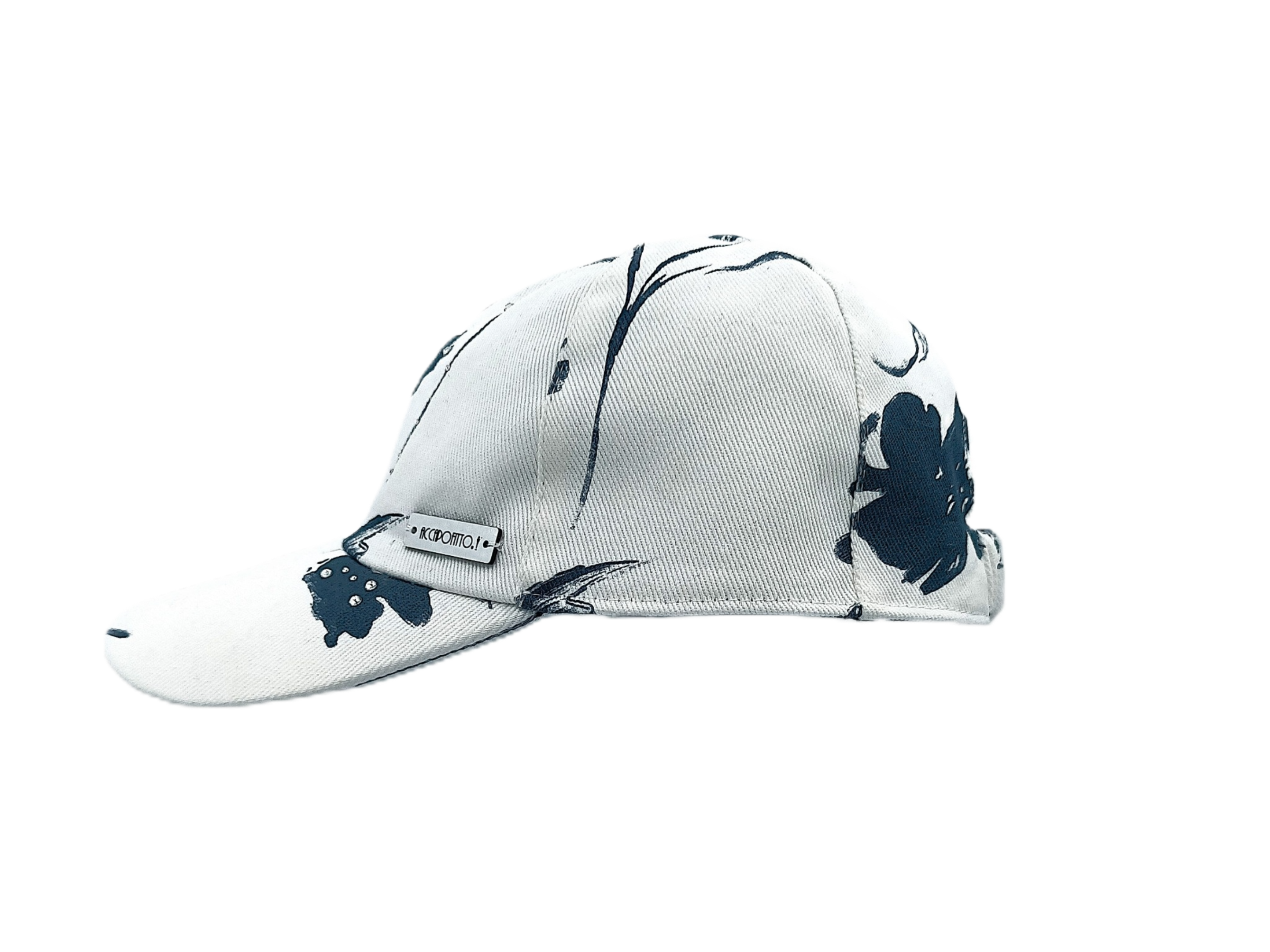 Cappello baseball del brand Accapofitto, in cotone bianco e disegno floreali blu, con strass. Visione laterale con targhetta argentata