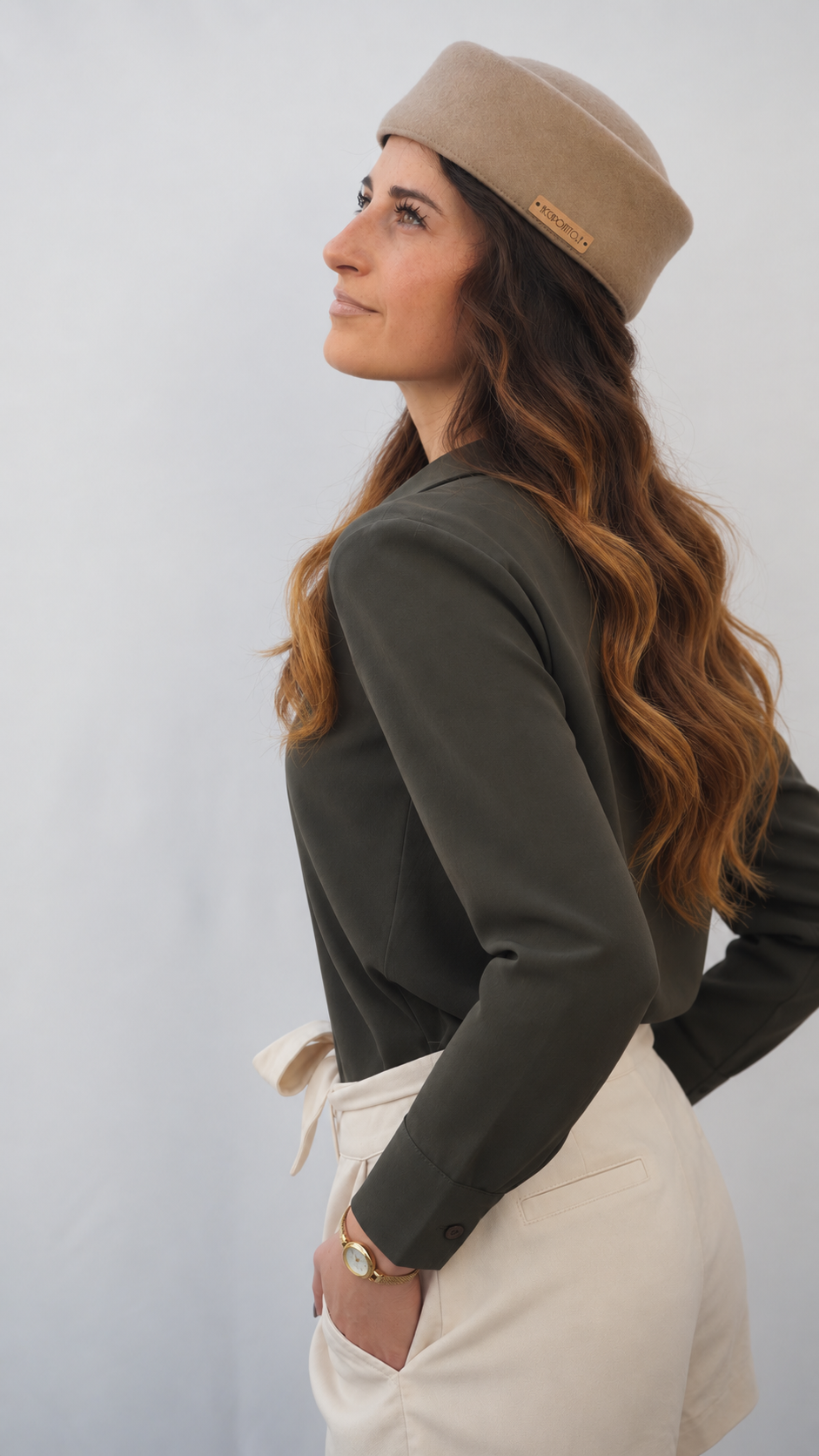 Cappello pillbox Chèrie del brand Accapofitto di feltro di lana beige con targhetta logo color rame, indossato da una modella