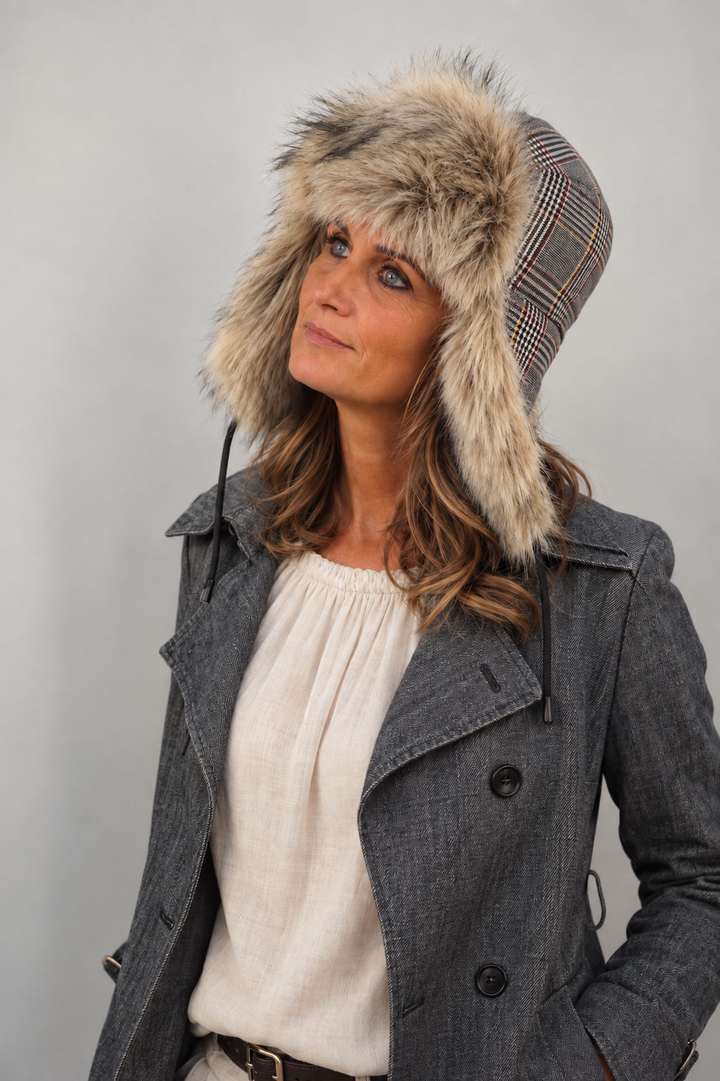 Cappello stile aviatore Mika del brand Accapofitto. Tessuto fantasia Principe di Galles multicolor, rifinito in ecopelliccia sui toni del grigio. Indossato da una modella