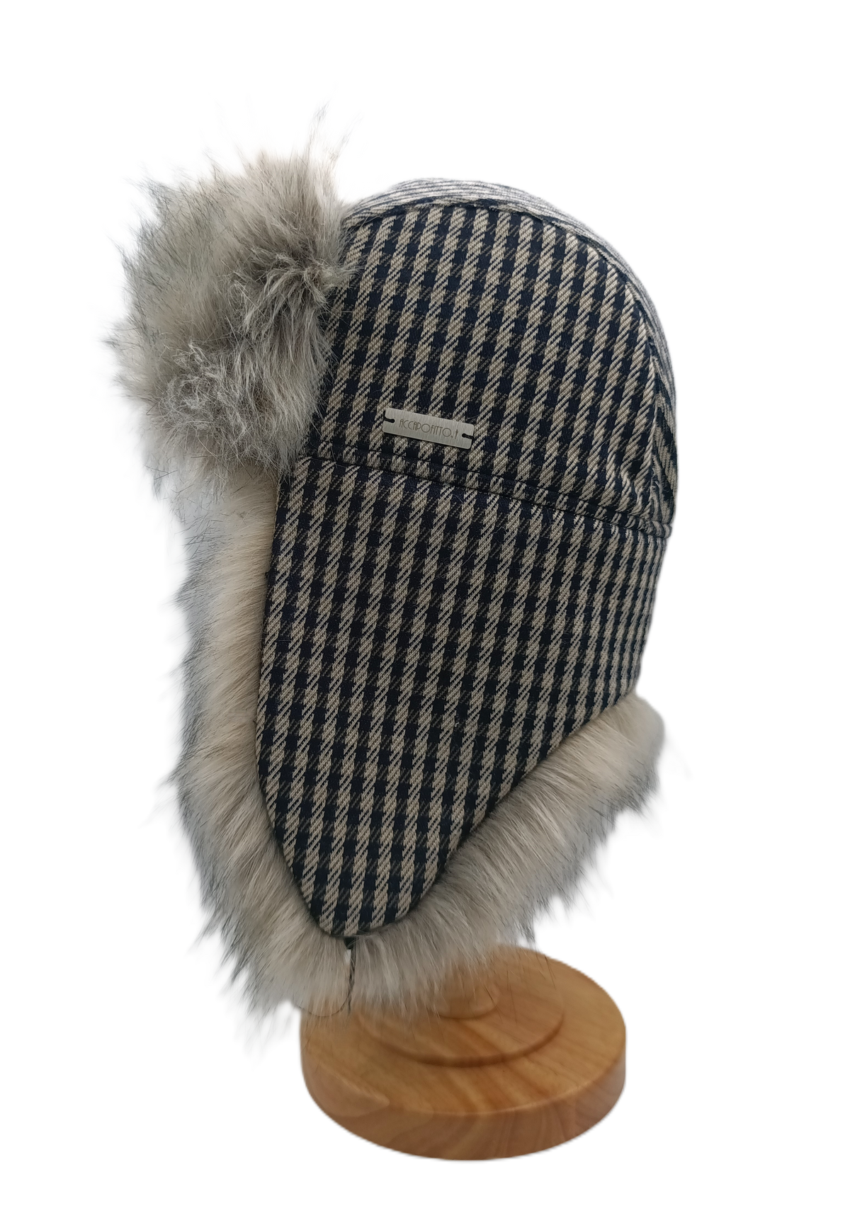Cappello aviatore Mika del brand Accapofitto. Tessuto esterno a quadretti blu e avorio stile pied de poulet, rifinito con ecopelliccia sui toni del grigio, su supporto di legno, visione laterale