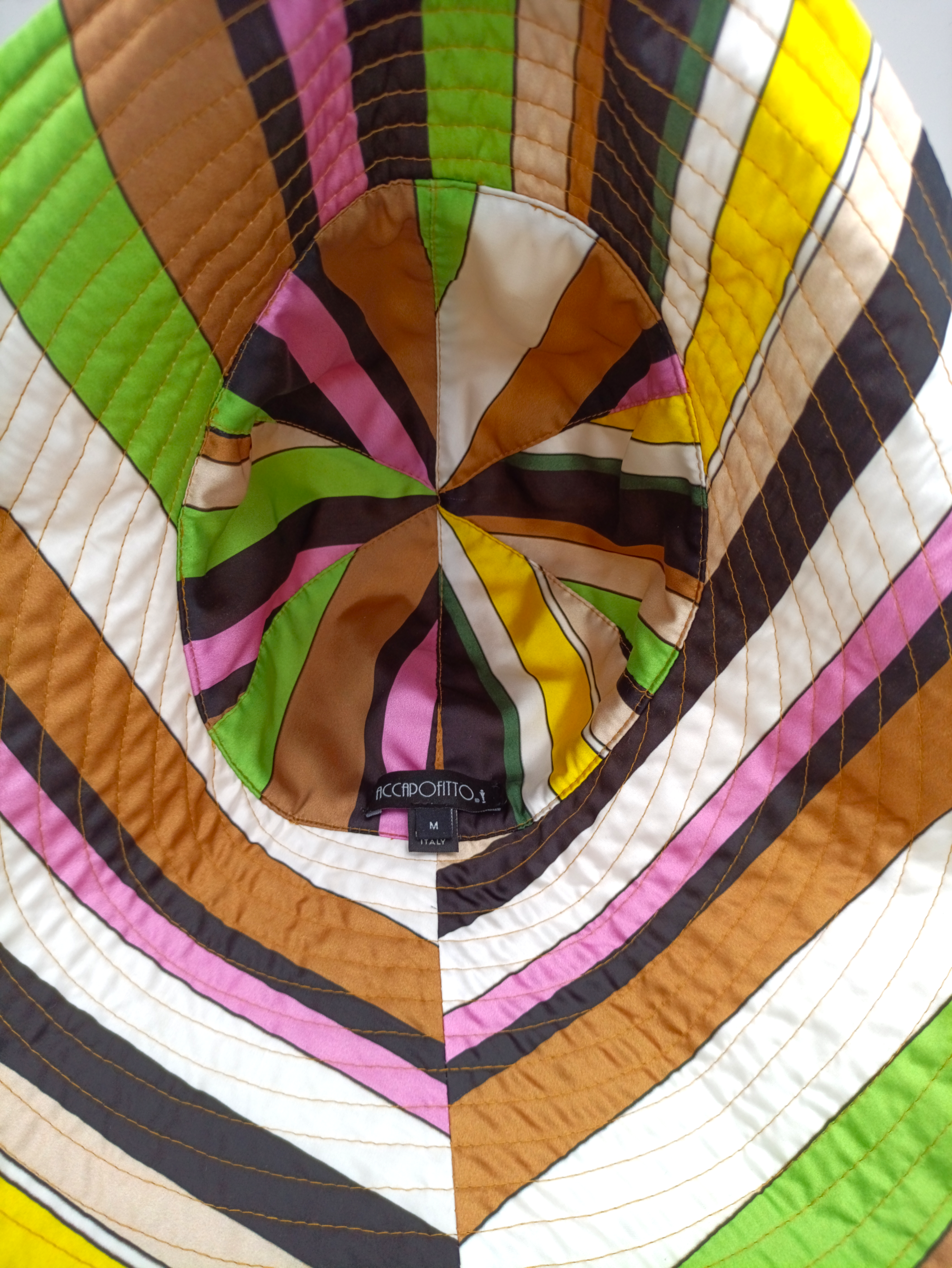 Cappello di lino color ocra del brand Accapofitto, con interno in viscosa tutta colorata. Modello cloche con ampia falda posteriore. Visione del tessuto interno colorato