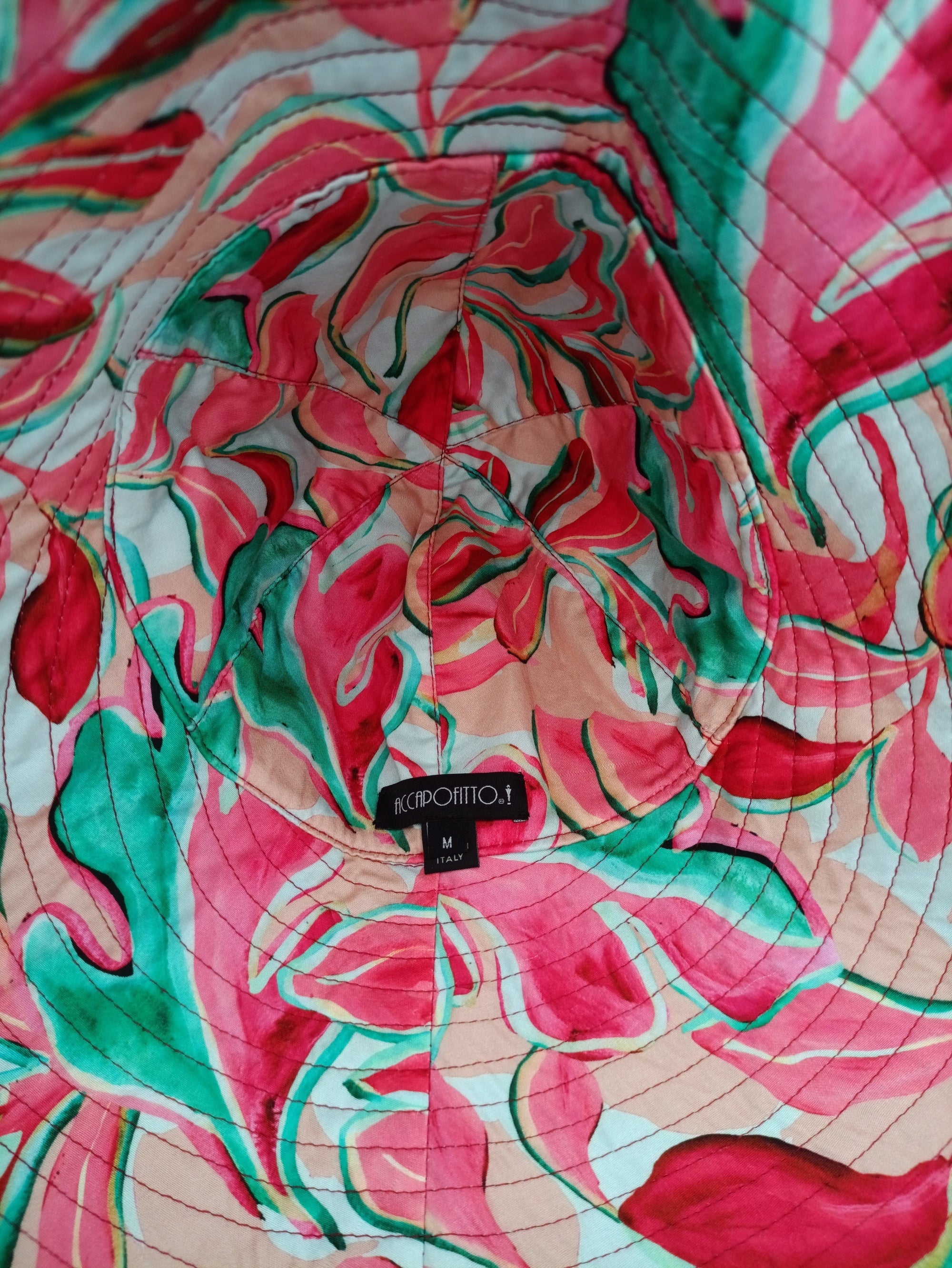 Cappello di lino color lampone del brand Accapofitto, con interno in viscosa tutta colorata (sui toni del verde, lampone, rosa e bianco. Modello cloche con ampia falda posteriore. Visione dell'interno