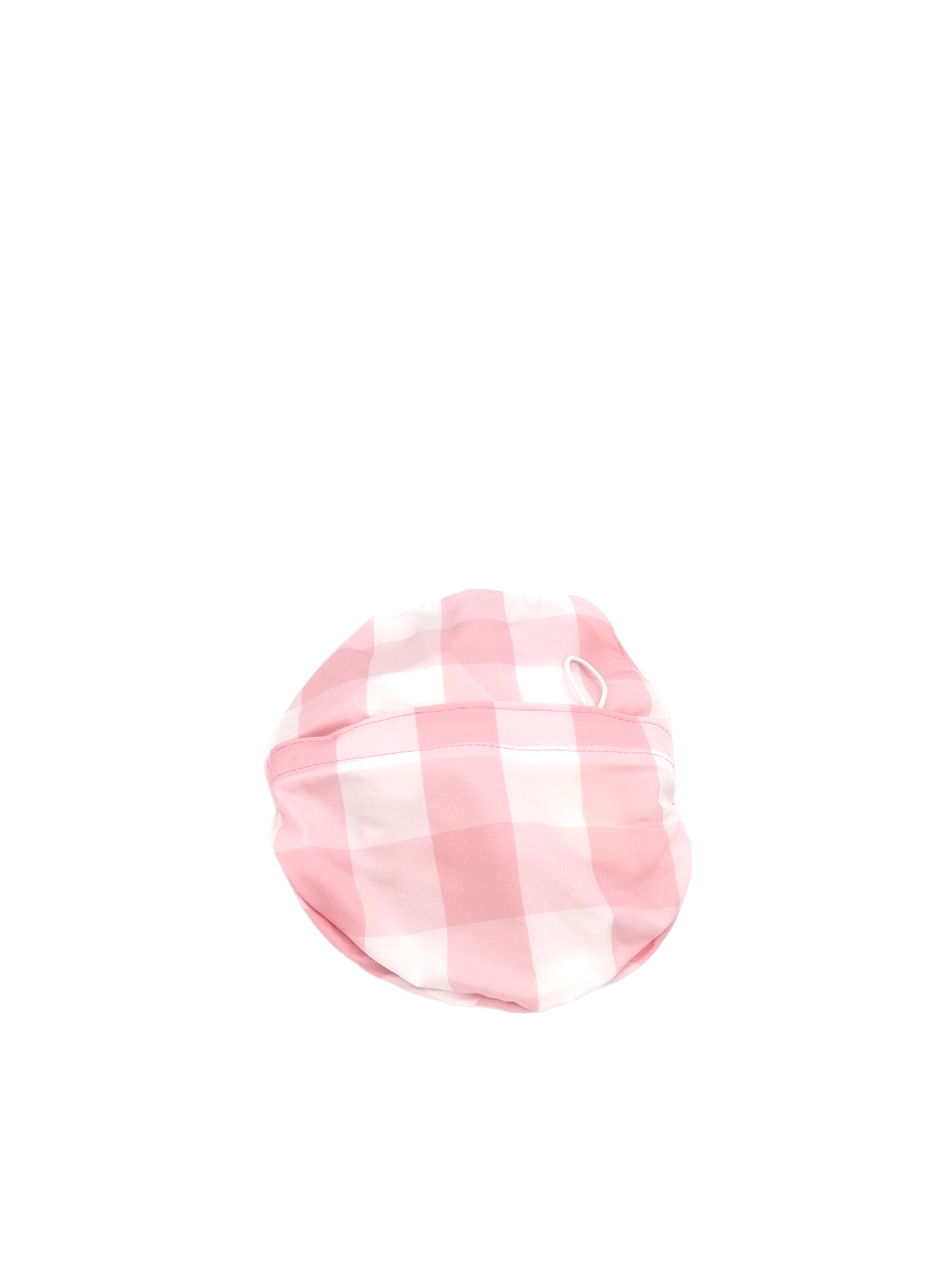 cappello bucket hat ripiegabile del brand Accapofitto. Tessuto a quadri bianchi e rosa. La foto mostra il cappello ripiegato nella sua tasca interna.