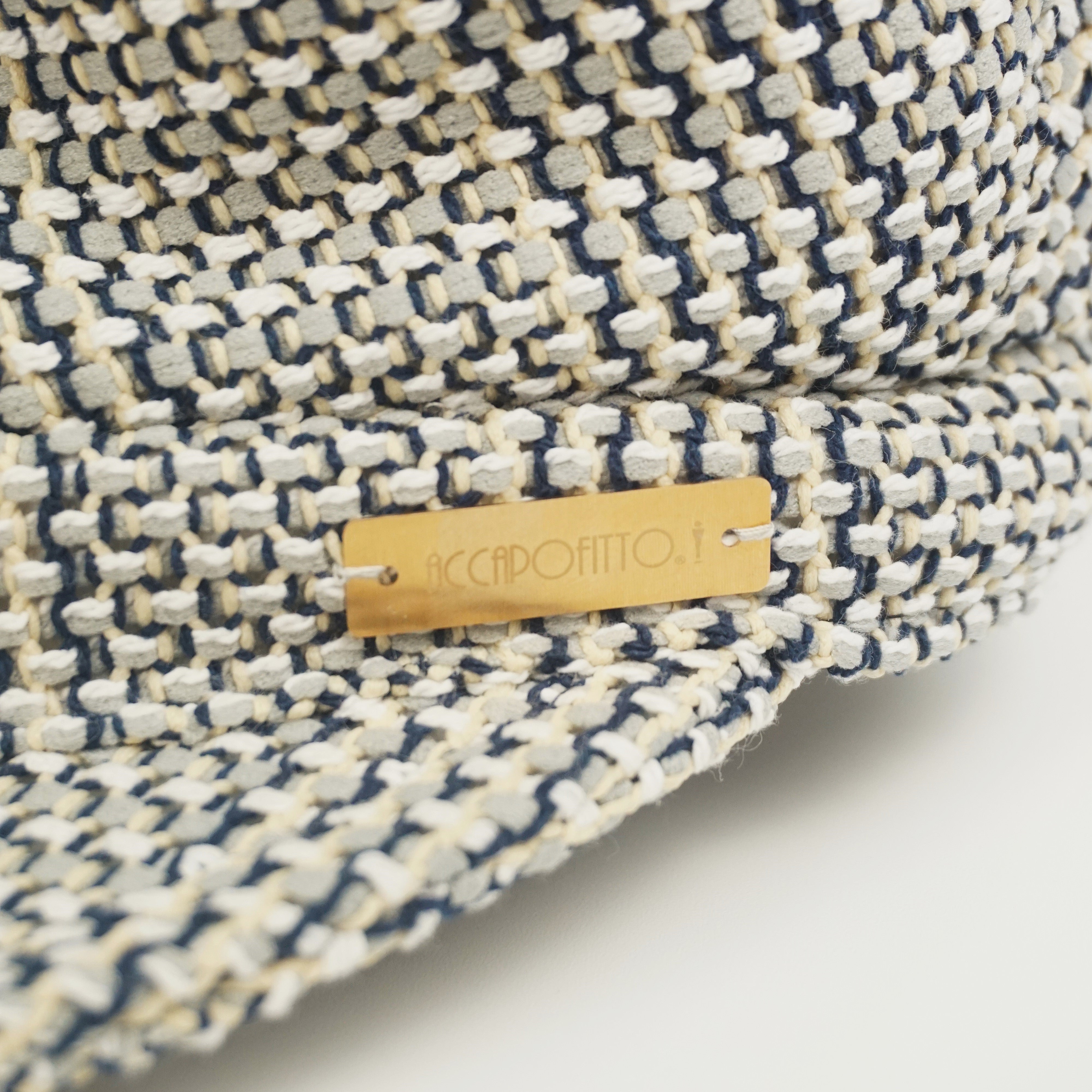 Cappello sailor hat del brand Accapofitto, con tessuto intrecciato sui toni del beige e del blu, targhetta dorata con logo, dettaglio