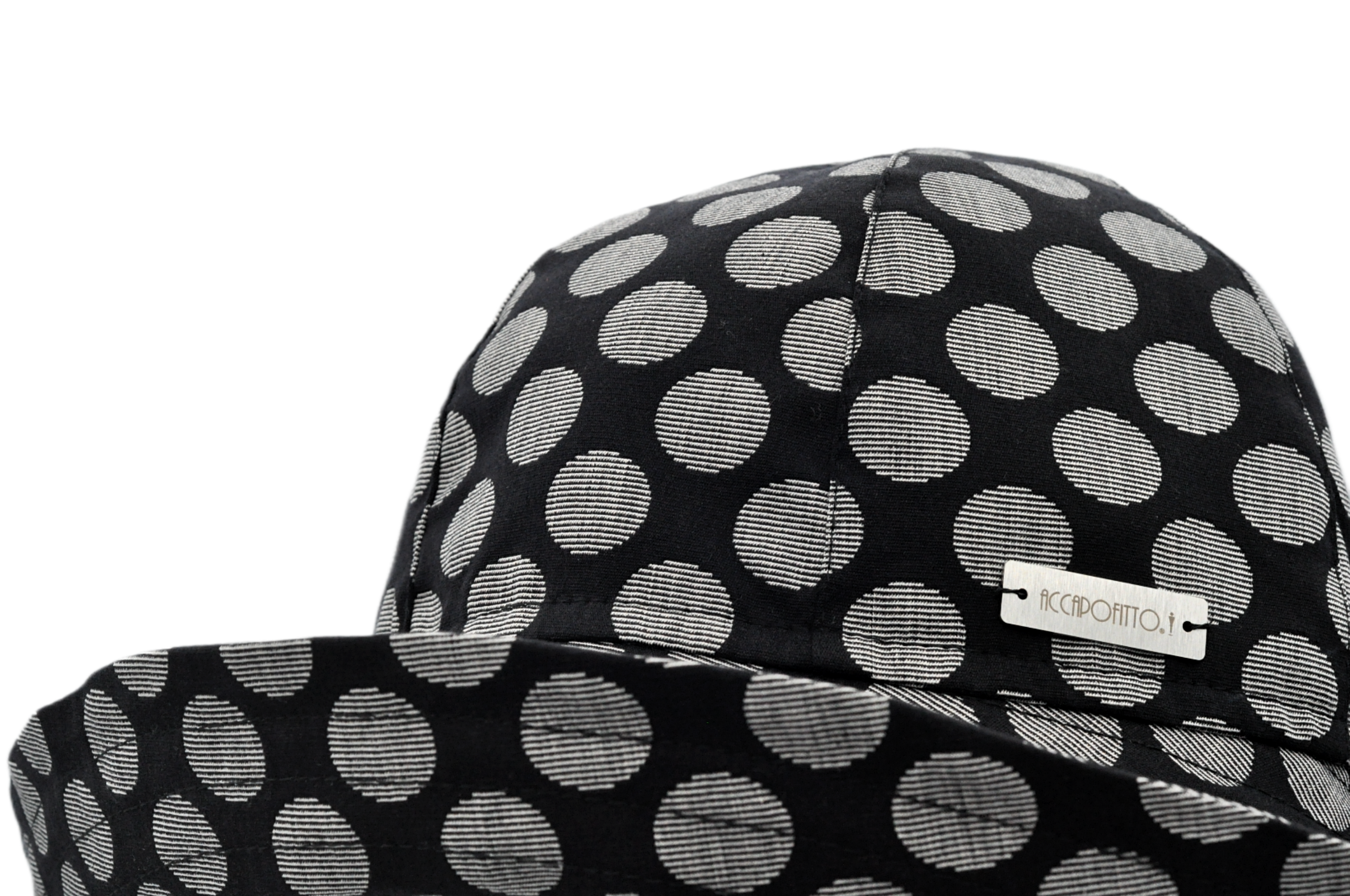 Cappello a cloche del brand Accapofitto, con tesa molto ampia sul collo. Fantasia sfondo nero e pois grandi chiari. Dettaglio